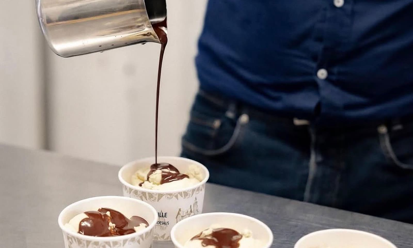 Guillaume giet warme chocoladesaus over bekertjes vanille-ijs